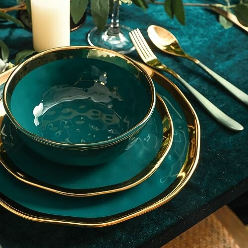 Elegant teal and gold dinnerware set with cutlery on a table.